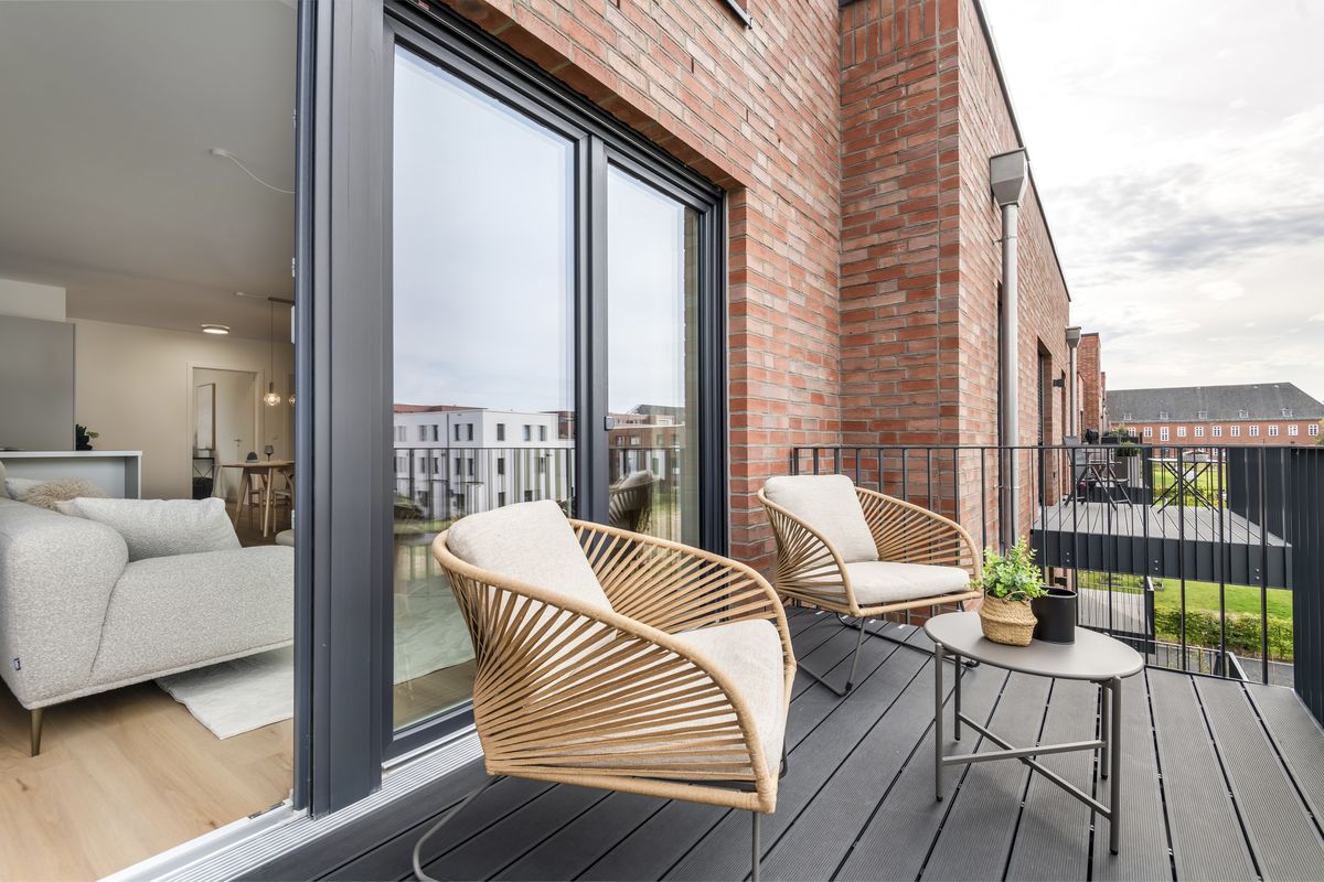 Foto eines Balkons mit Sitzgruppe vor Klinkerfassade, links der Wohnbereich